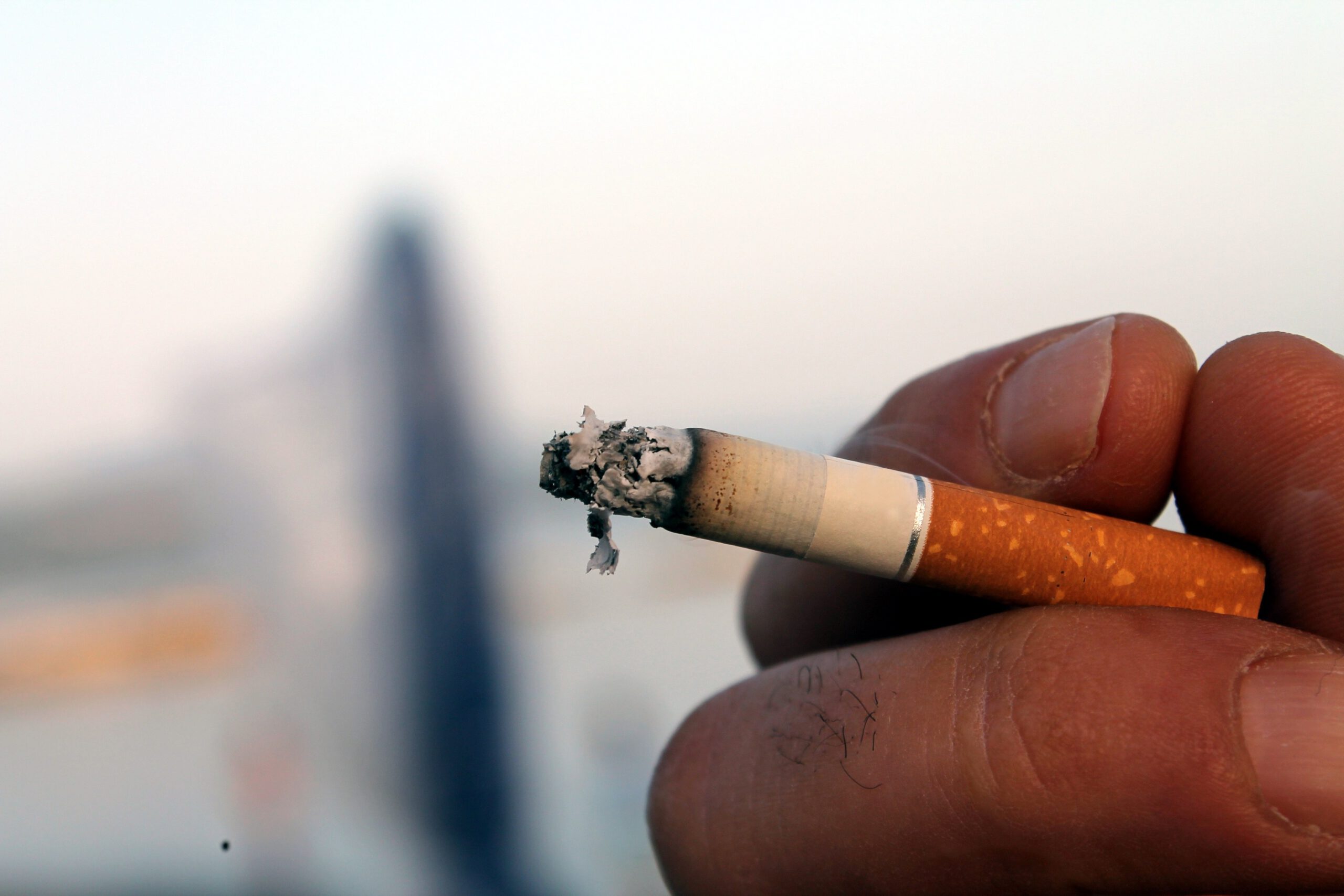 une main tenant une cigarette qui se consume